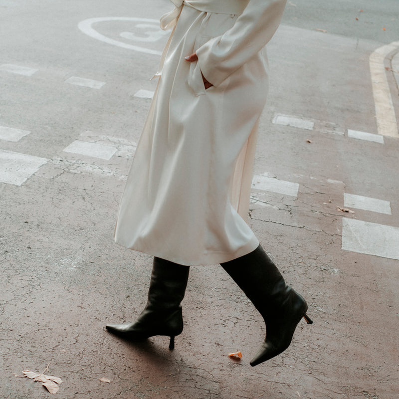 Girl walking in women's black leather boots and a white coat.