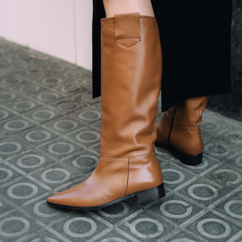 Vista de cerca de unas botas para mujer en piel marrón, con poco tacón y altas de caña